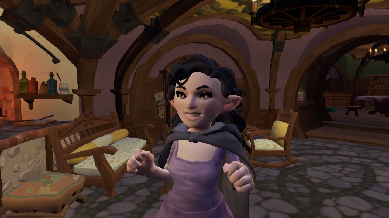 Uma fêmea hobbit de contos do Condado enfrenta a câmera, sorrindo com as duas mãos levantadas. Ela tem longos cabelos pretos, pele pálida e está usando uma capa preta e vestido roxo.